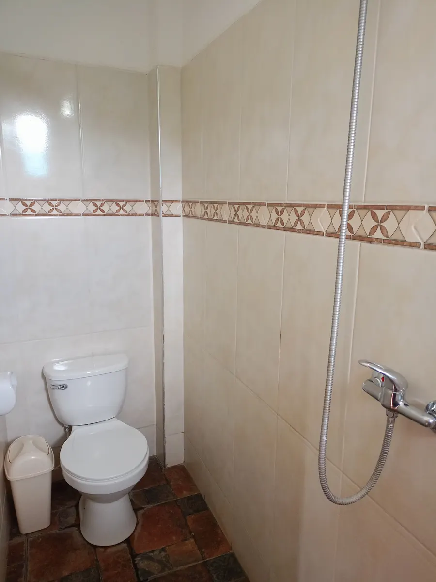 Baño privado con ducha e inodoro, paredes con cerámica