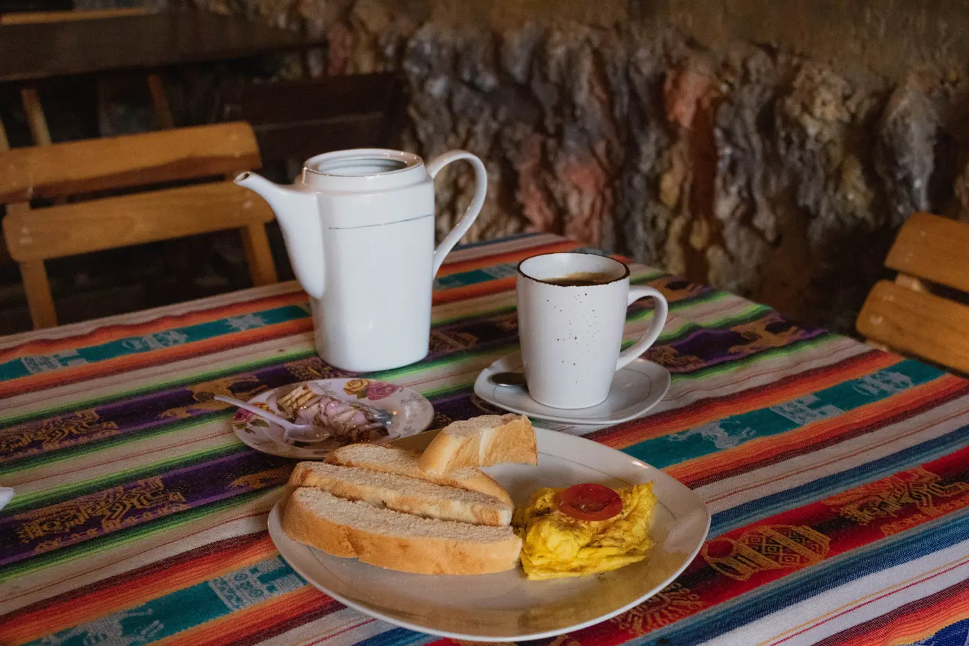 Desayuno con té, pan tostado y huevos sobre mantel andino